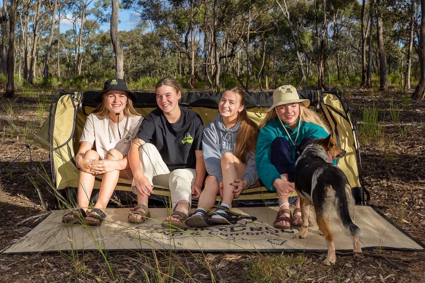 Four girls sitting in Single Swag with a blue heeler dog