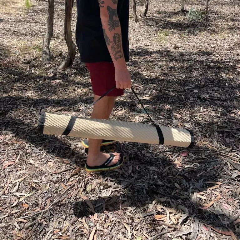 Person using the included elastic straps to easily carry rolled up Swag Mat.