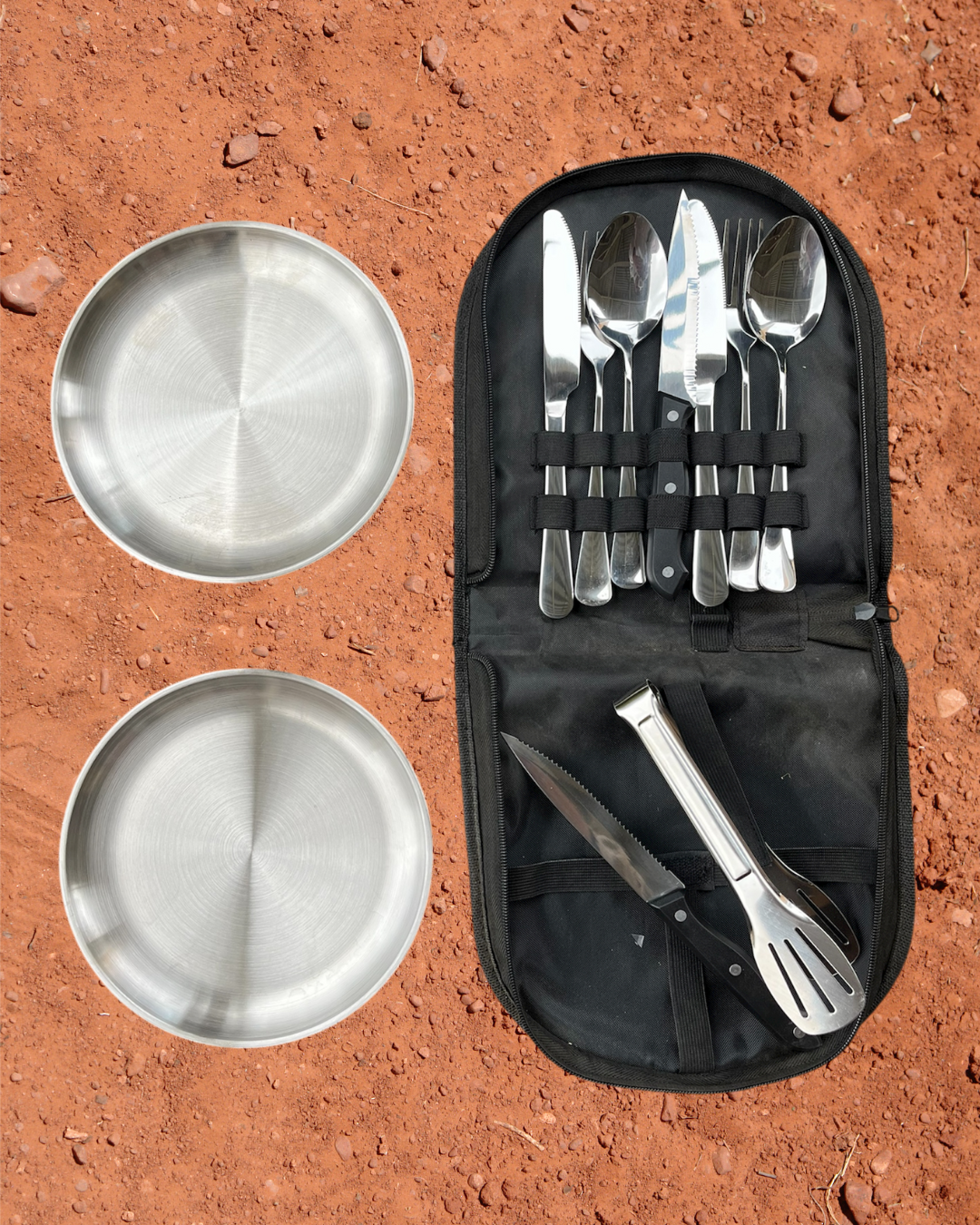 Camping Utensil Set for your camp kitchen. Set of silver cutlery and plates in a black carry case on a red dirt background.