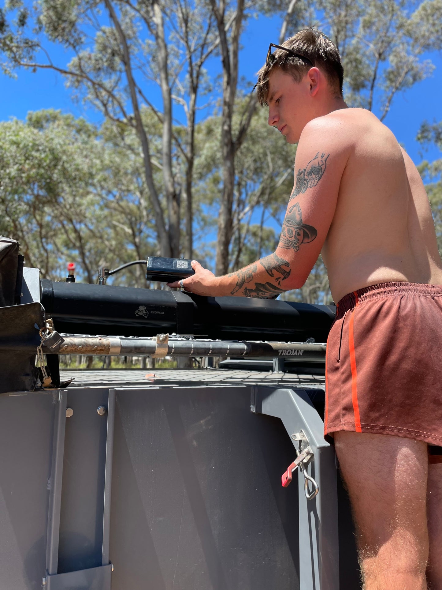 Young man using the rechargeable air compressor to pressurise the Solar Shower System.