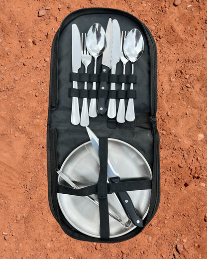 Camping Utensil Set for your camp kitchen. Utensil Set of silver cutlery and plates in a black carrying case on a red dirt background.