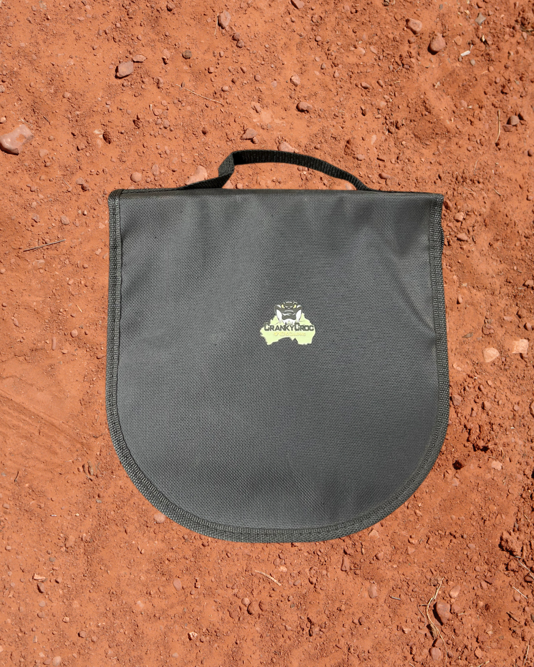 Camping Utensil Set for your camp kitchen. Utensil set of silver cutlery and plates in a black carrying case on a red dirt background.