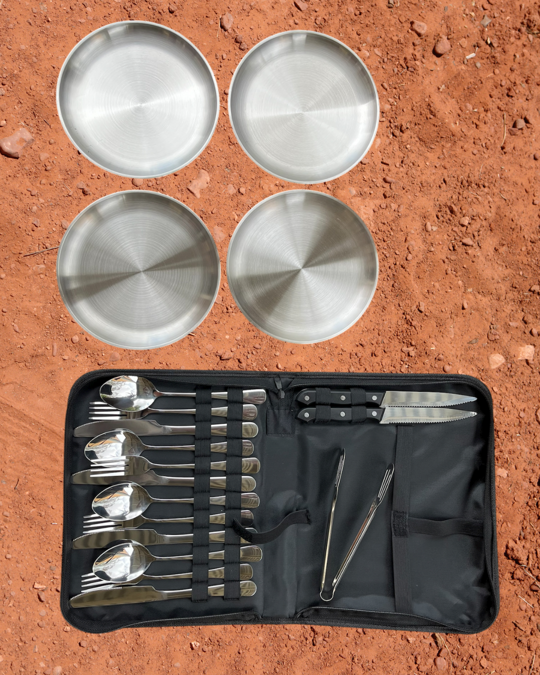 Camping Utensil Set for your camp kitchen. Utensil set of silver cutlery and plates in a black carrying case on a red dirt background.