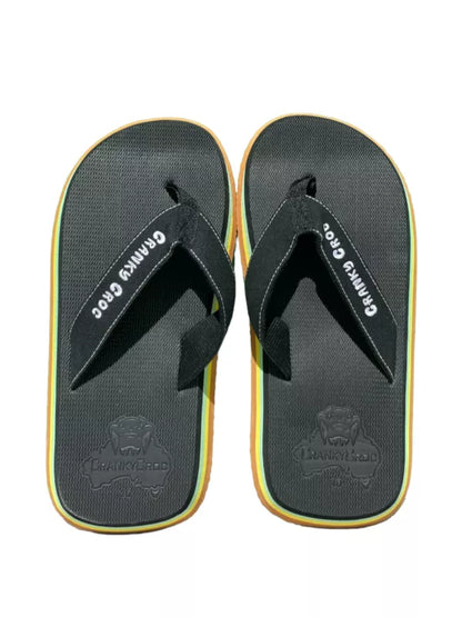 A pair of Cranky Croc Great Aussie Pluggers– The pluggers are black and sides are yellow, green and brown and look retro. The thongs are a sufer joe thong style. the image is taken on a white background. 