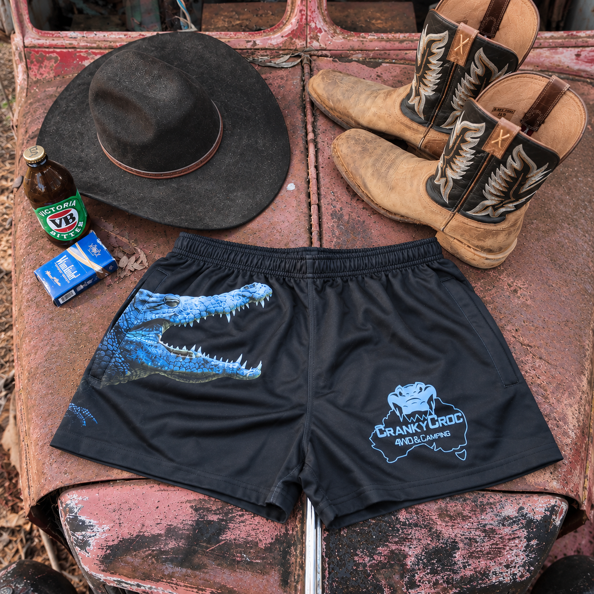 Black Country Aussie Footy Shorts on a 4wd bonnet next to a pair of country boots, country cowboy hat and a beer.