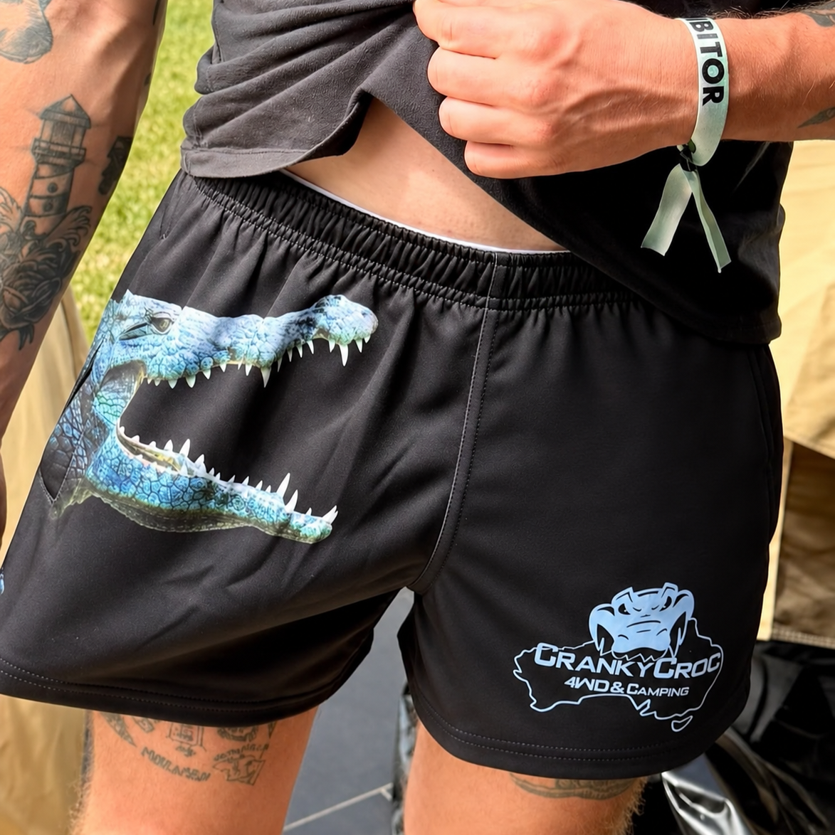Person wearing black Aussie Footy Shorts with a crocodile graphic and 'Cranky Croc' branding.