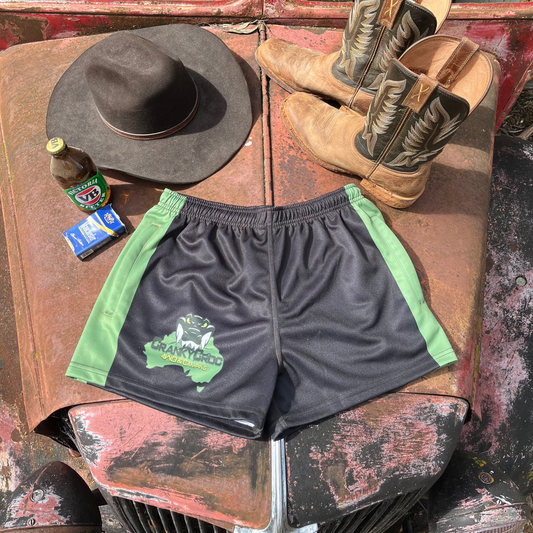 Black with green Country Aussie Footy Shorts on a 4wd bonnet next to a pair of country boots, country cowboy hat and a beer.