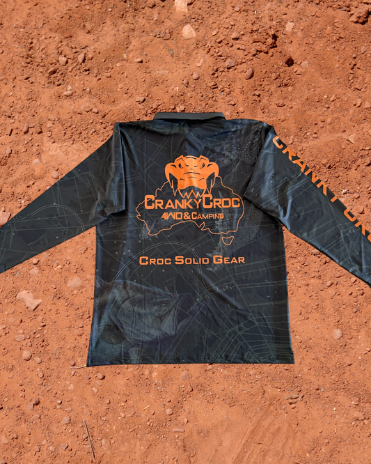 Back of dark green long sleeve fishing shirt / hunting shirt. The fish shirt has fluro orange 'Cranky Croc' branding with a crocodile and barramundi design on a red dirt background