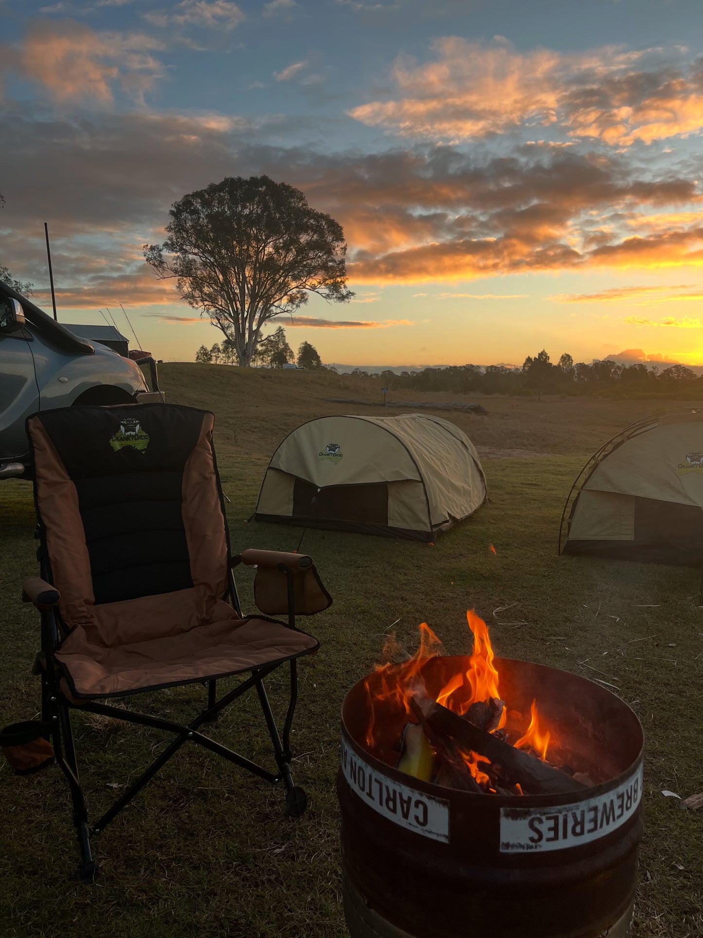 Camping scene with a camping chair, fire pit, and swags at sunset.