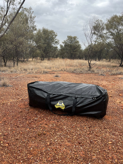 Black swag bag with a logo on a dirt ground with trees in the background