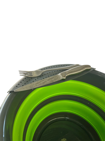 Collapsible green and grey bucket with a knife and fork on strainer with a white background