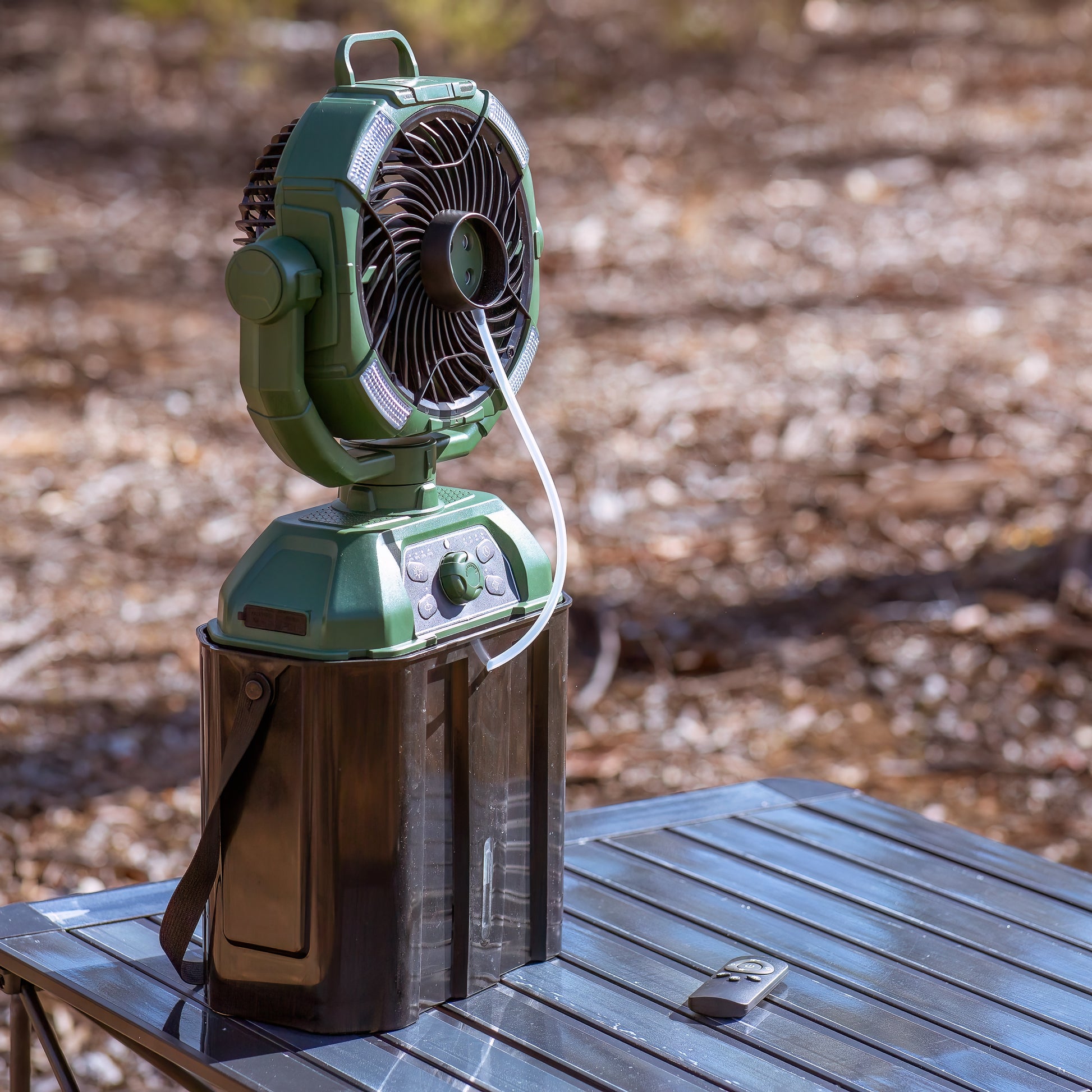 Large misting fan in an outdoor setting sitting on a camping table. The camping fan is coloured green