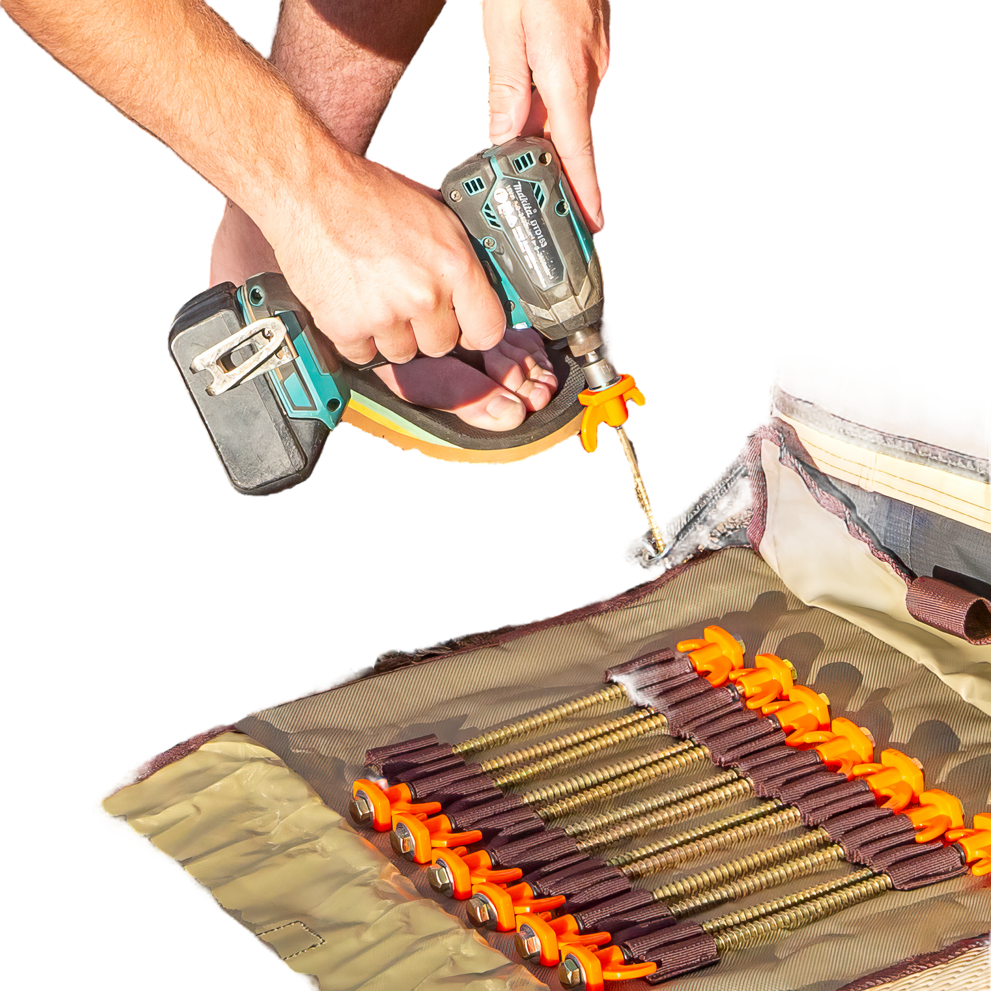 A person is using a hand drill to drive 'screw in tent pegs' into the ground, with the beige roll-up bag of pegs visible in the foreground.