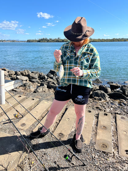 Person fishing by a body of water wearing a hat and wearing Aussie Footy Shorts