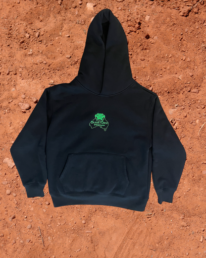 Front view of black hoodie with a green embroidered logo on a red dirt background