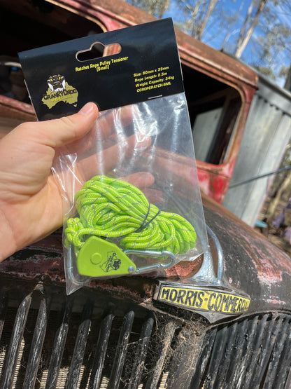 Hand holding green Cranky Croc branded tie down straps in a clear packaging. The man is holding the ratchet straps in front of an old red Morris vehicle