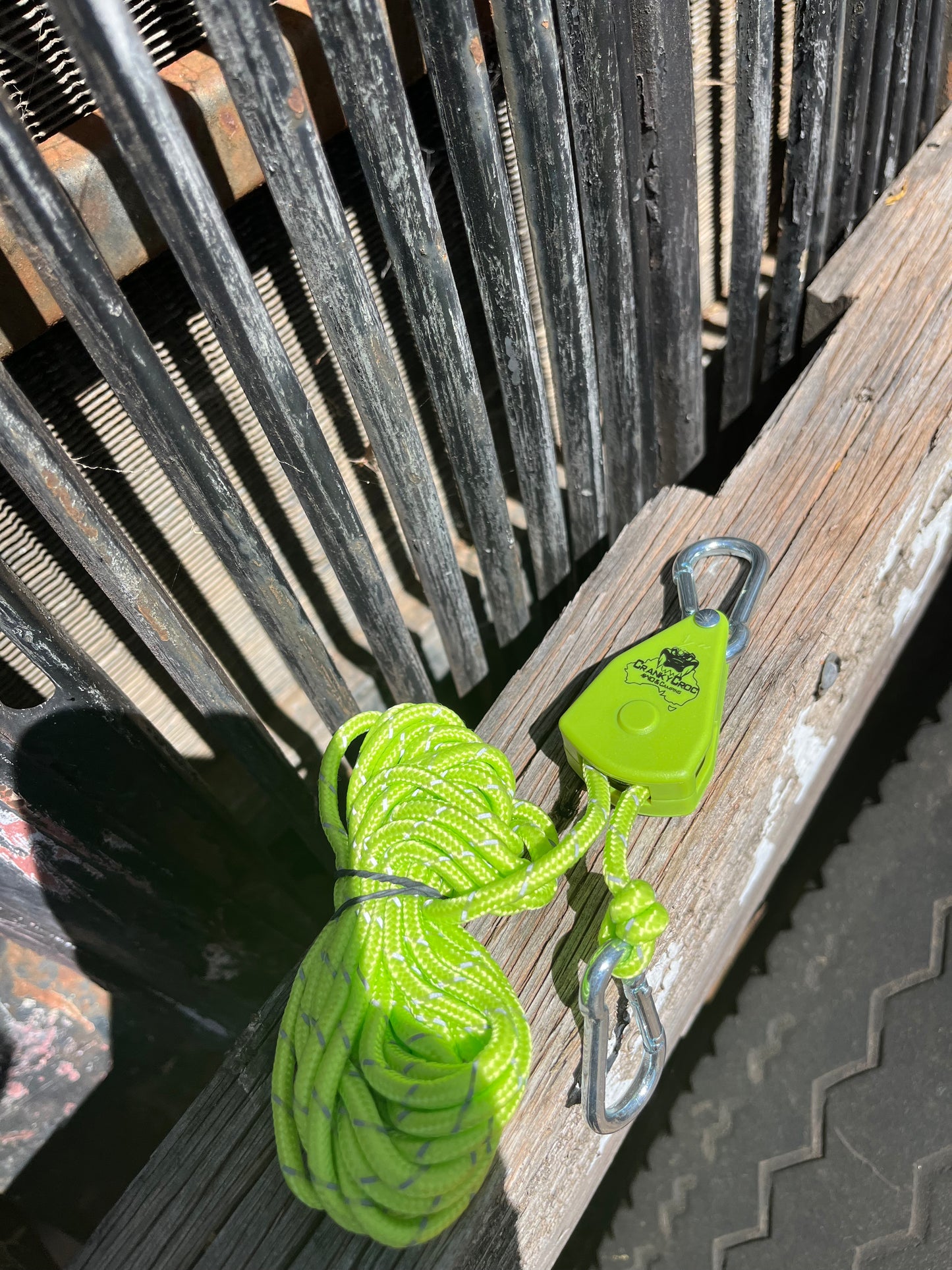 Green Cranky Croc branded tie down strap. The ratchet straps is on a timber