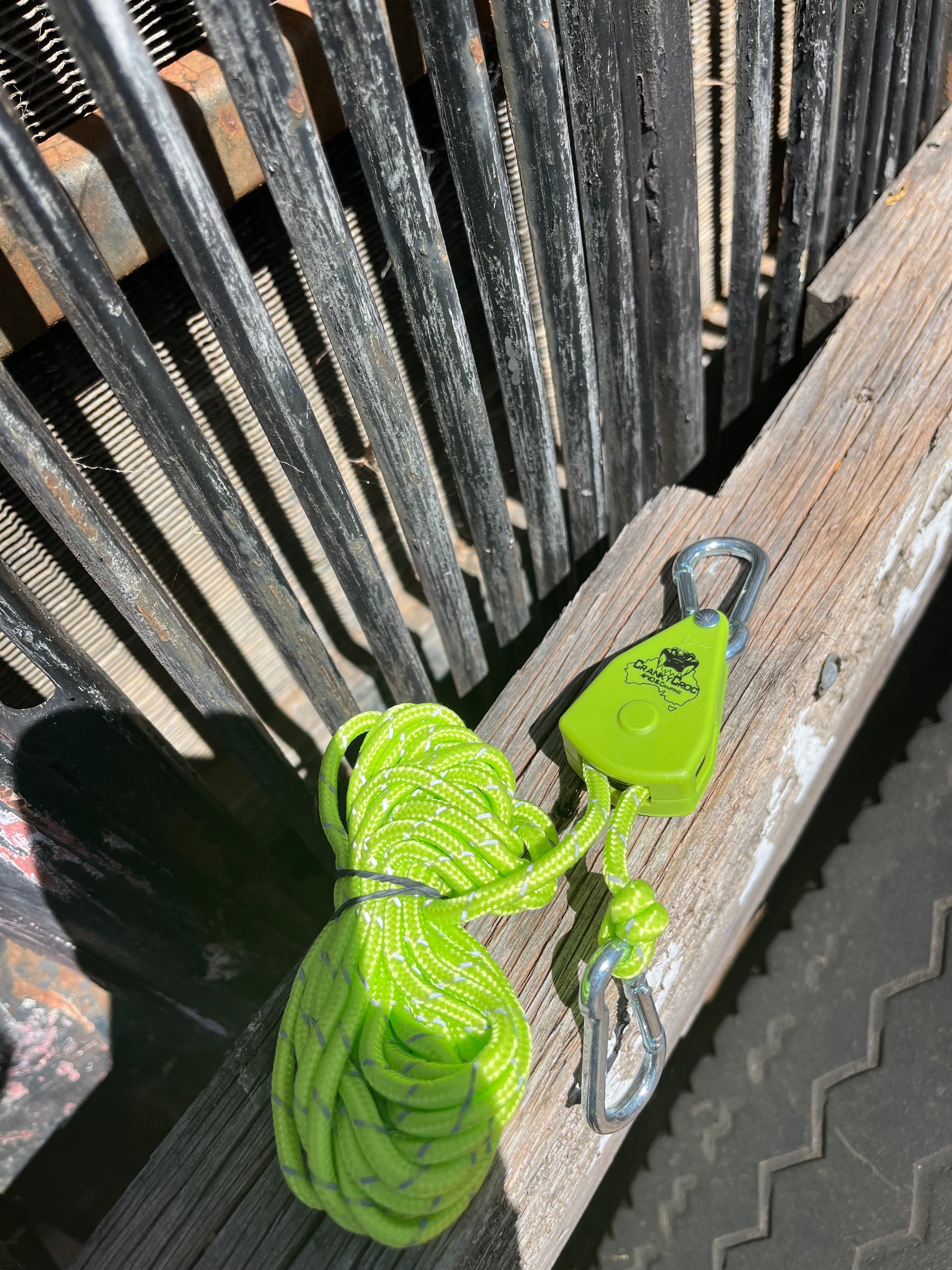 Green Cranky Croc branded tie down strap. The ratchet straps is on a timber