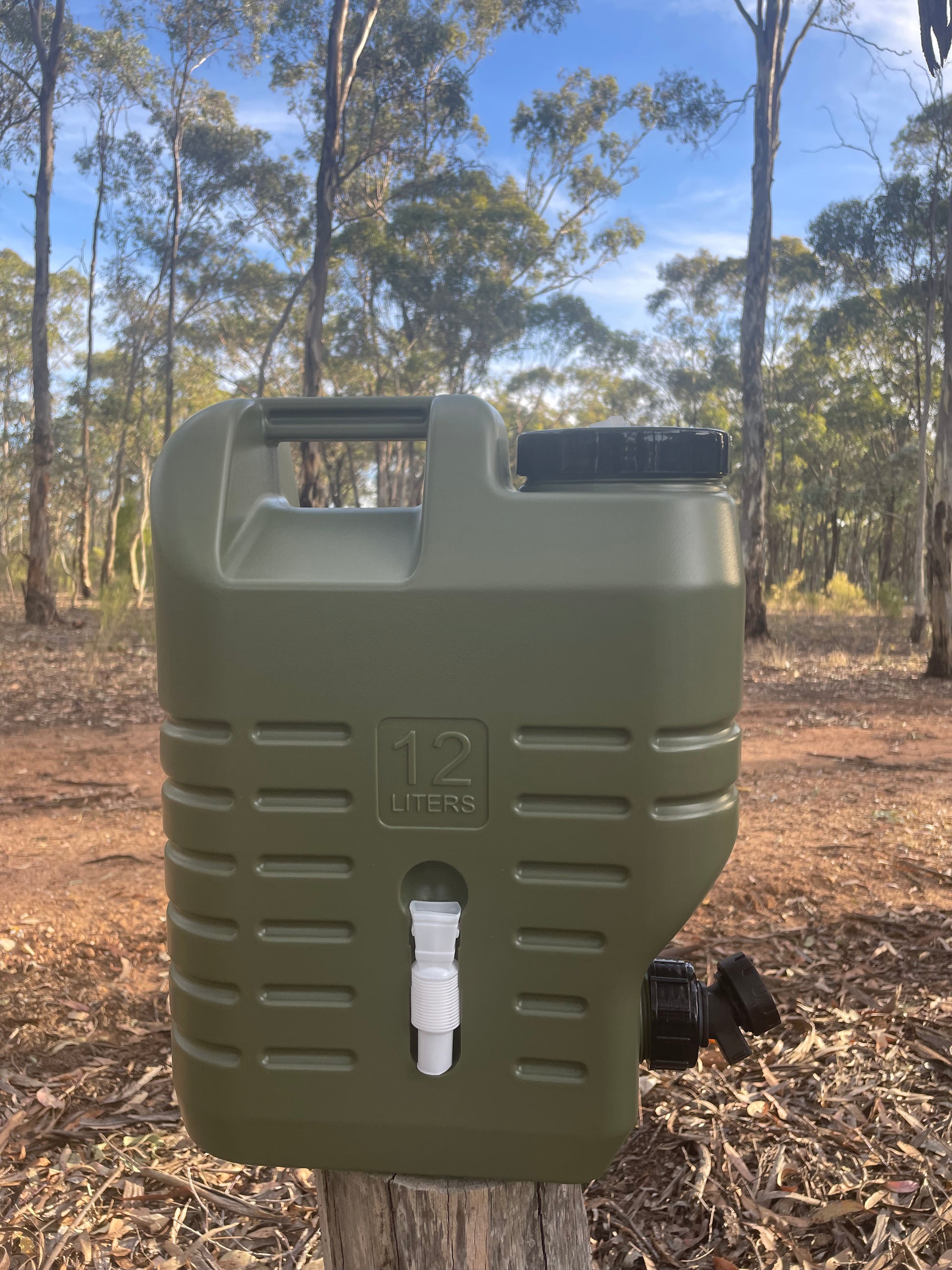 Water storage drum used for camping sitting on log in bushland 