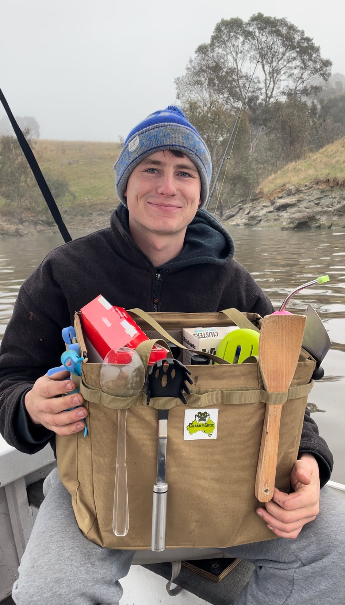 Young man sitting in fishing boat holding a Outdoor Collapsible Hamper.