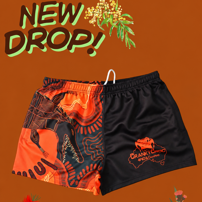 Pair of indigenous art footy shorts on an orange background with floral elements and 'NEW DROP!' text.
