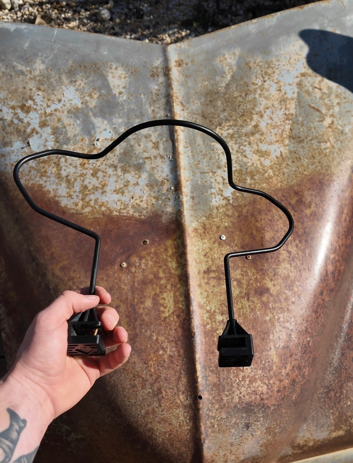 A person's hand holding a black metal car seat hat holder 