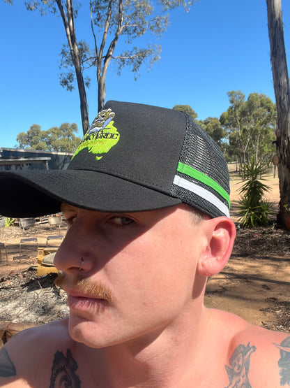 Man wearing a black trucker cap with a Cranky Croc logo outdoors. The country trucker cap has green and white stripes across the sides