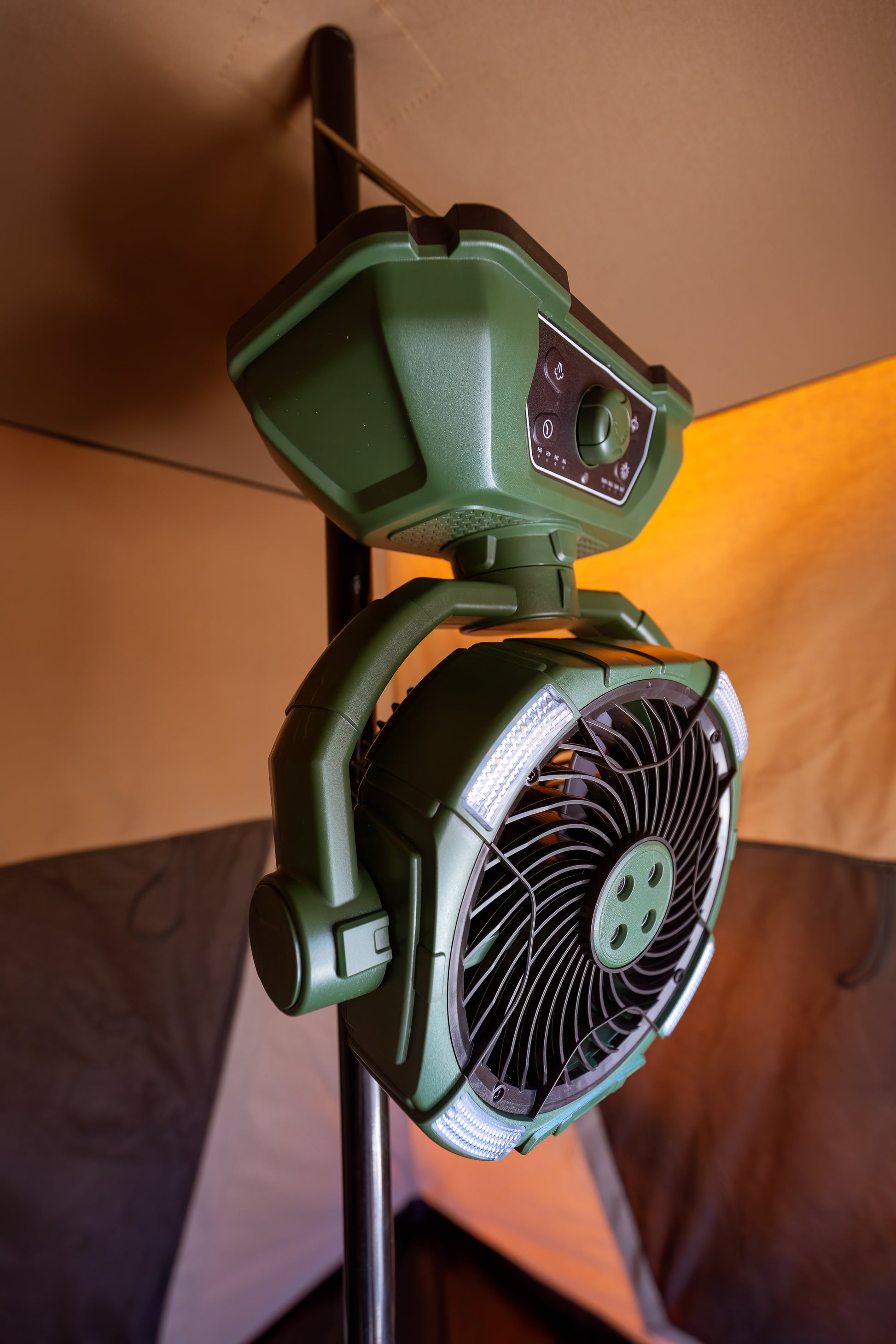 Camping misting fan hanging in a tent. The camping fan is coloured green