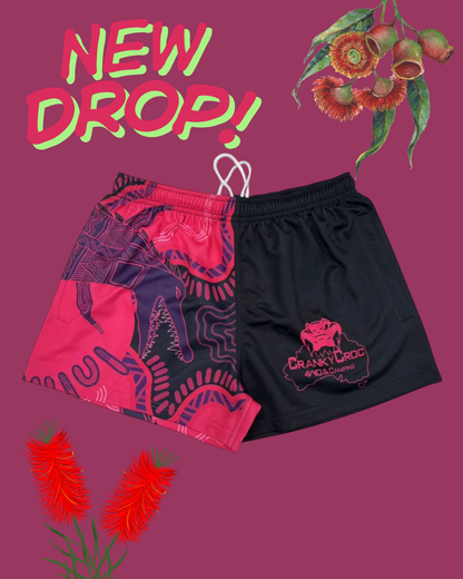 Pair of indigenous Footy Shorts on a purple background with floral elements and 'New Drop!' text.