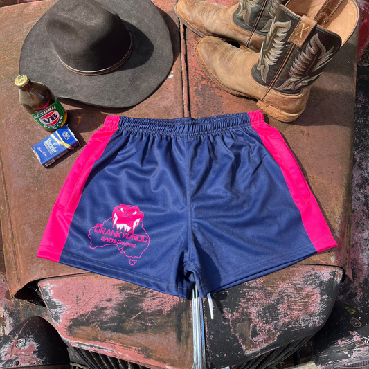 Pink and Navy Country Aussie Footy Shorts on a 4wd bonnet next to a pair of country boots, country cowboy hat and a beer.