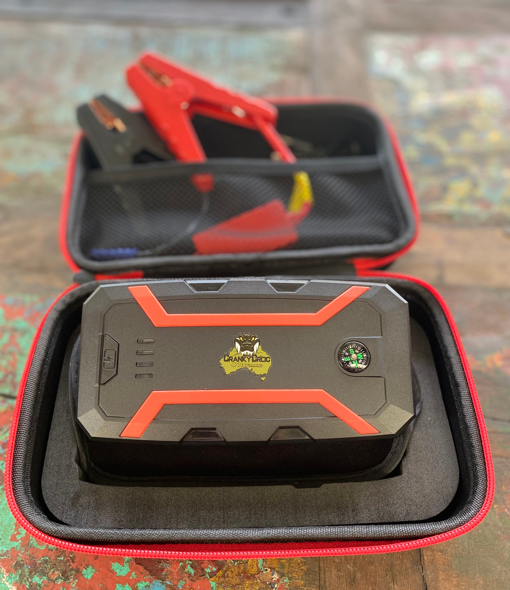 Battery Jump starter in protective case, with Cranky Croc logo on timber background