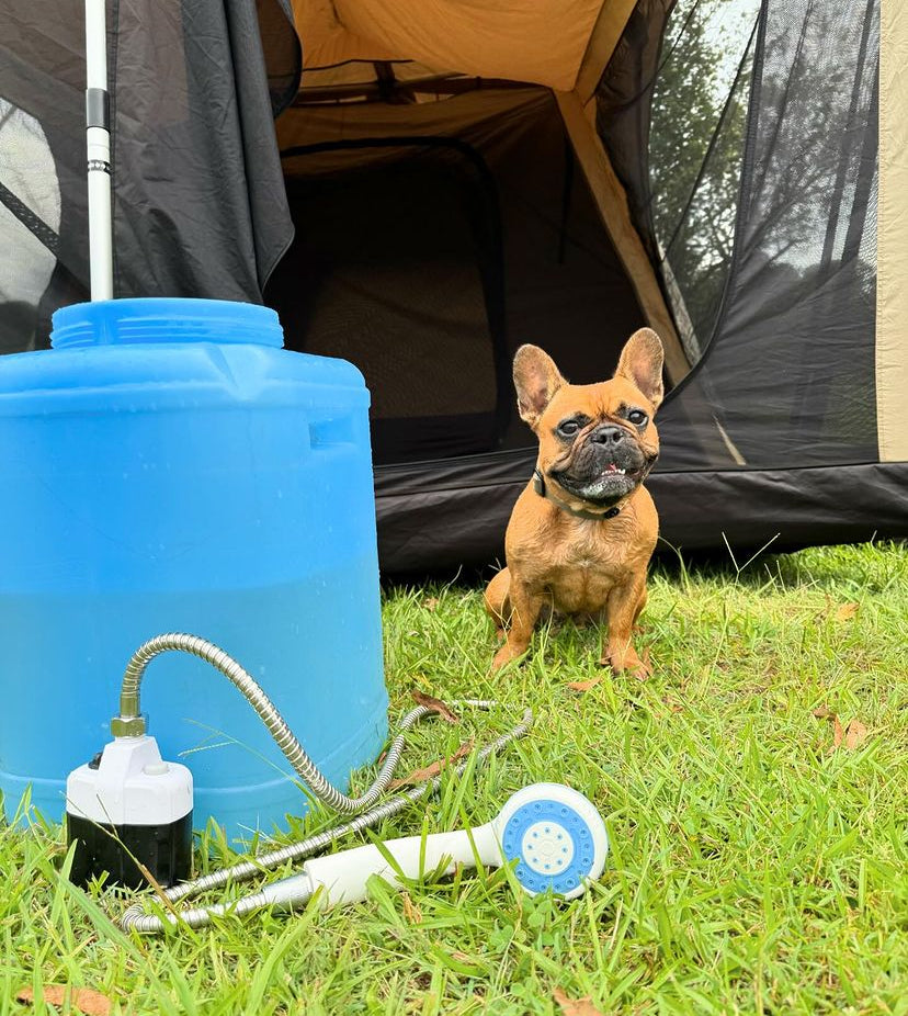 Rechargeable portable-shower next to blue water drum, in front of a dog and tent