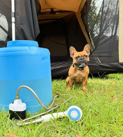 Rechargeable portable-shower next to blue water drum, in front of a dog and tent