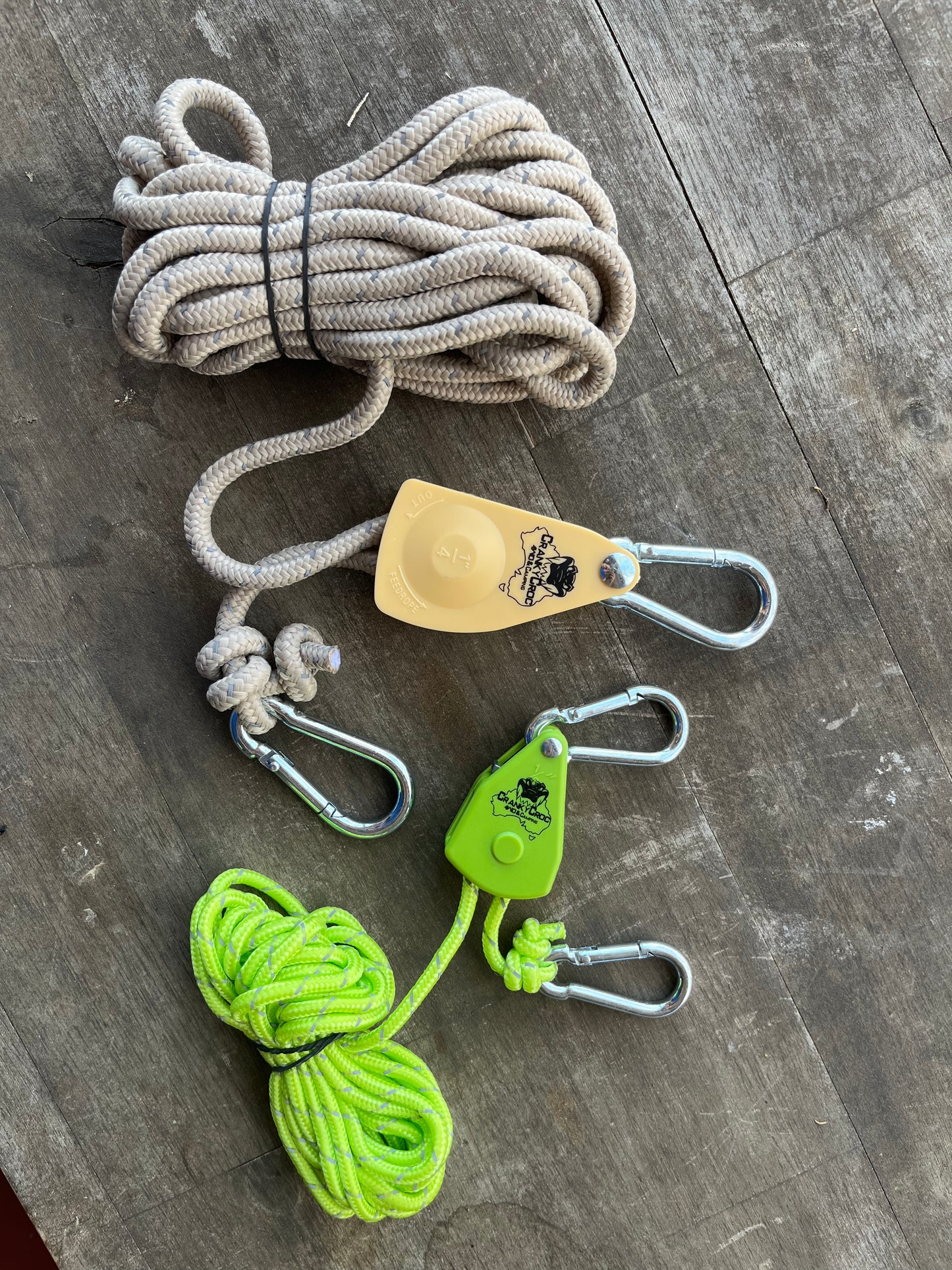 Two Cranky Croc branded tie down straps. The ratchet straps are on a timber background