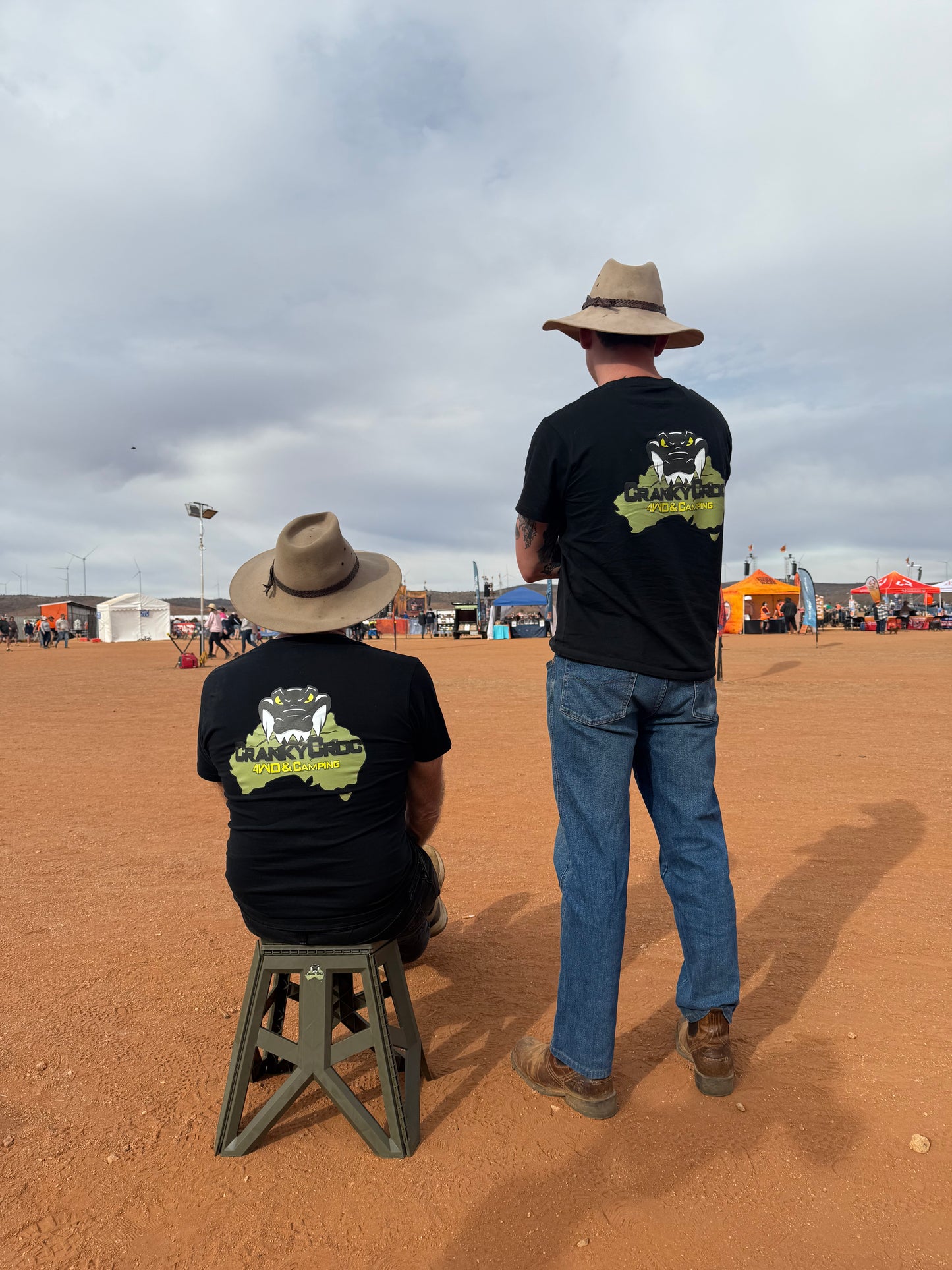Two men wearing Cranky Croc branded black tees and other country apparel in an Aussie outback setting with red dirt