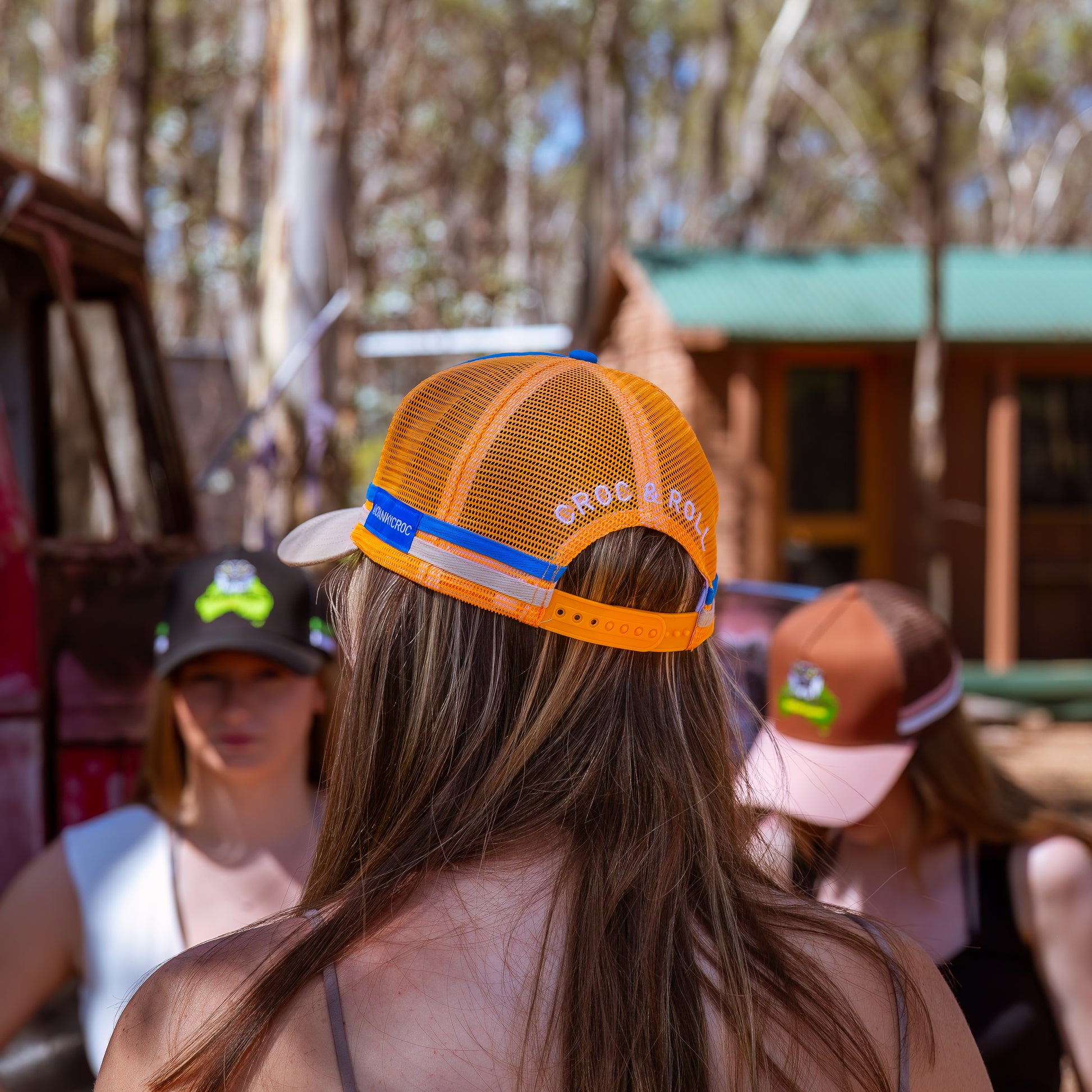 Woman wearing an orange and blue trucker cap with 'Croc N Roll' branding.