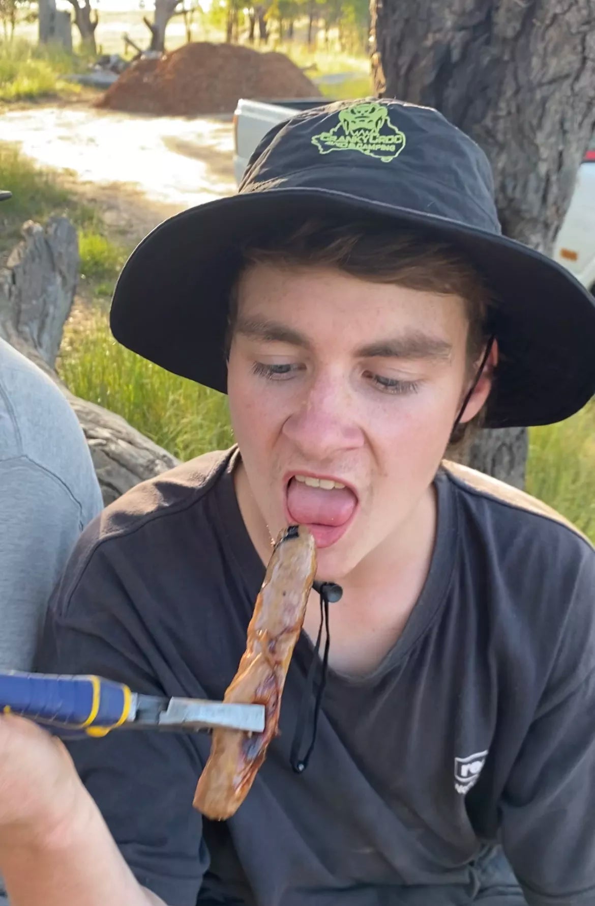 Young man eating a sausage while wearing a Folding Pouch Hat